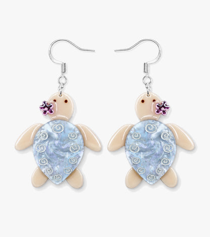Cream turtle earrings with pale blue pearly shells, white swirl details, and small pink flowers.